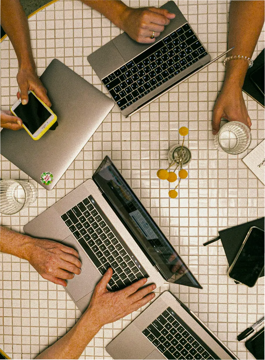 A group of people having  a meeting with their laptops and phones out