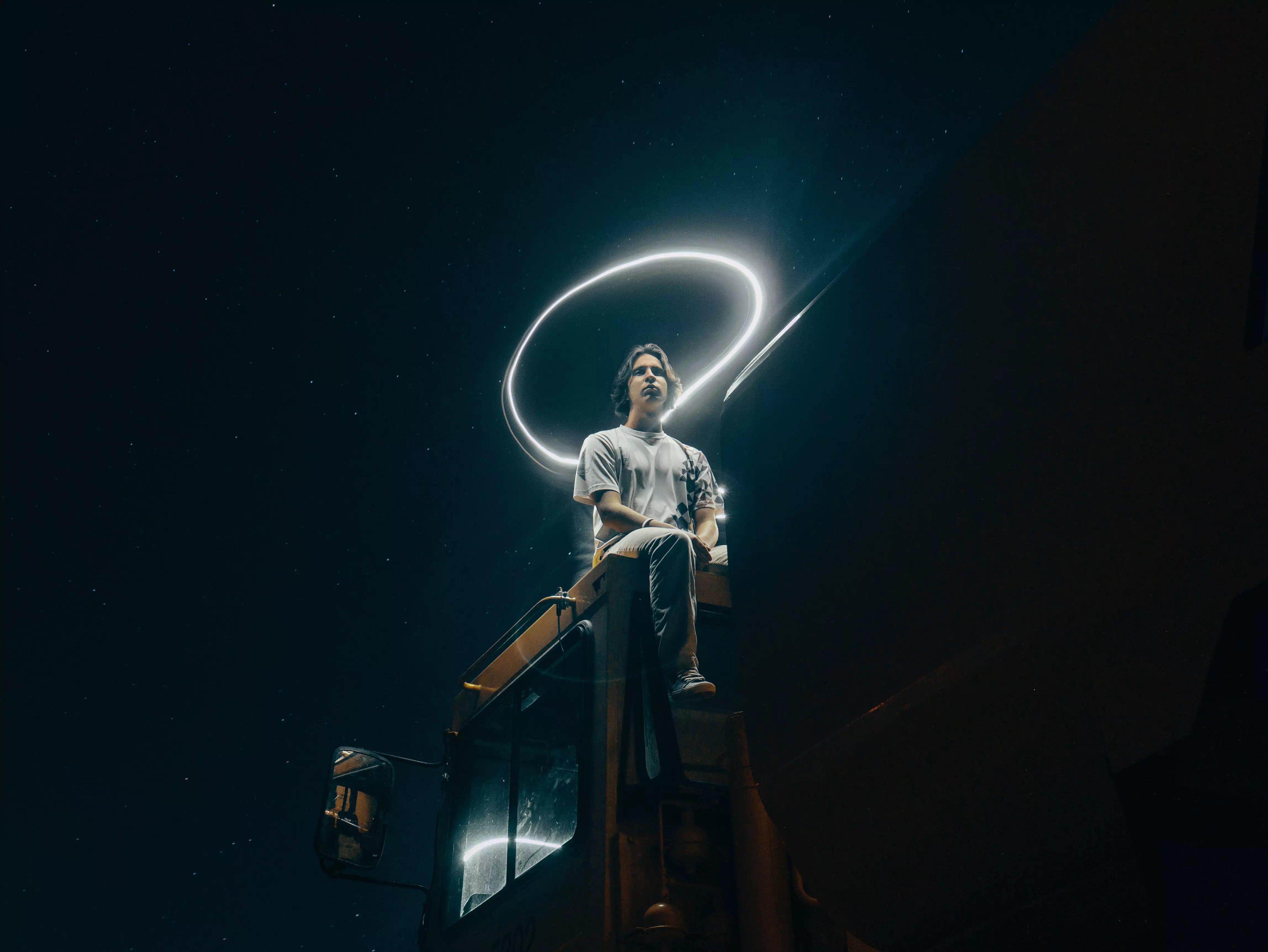 Someone sitting below the night sky with a glowing magic ring above them.